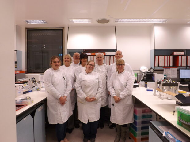 Image of eight laboratory scientists standing together for a photograph.