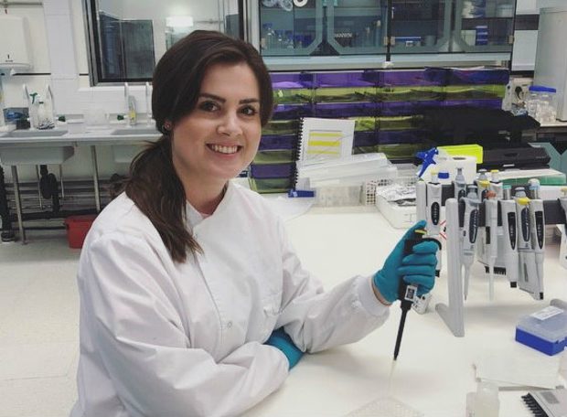 Female scientist holding a pipette and looking into camera