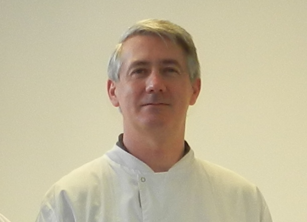 Male scientist wearing a lab coat and looking into camera