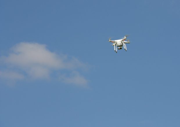White drone flying against a blue sky