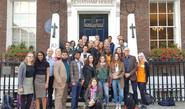 Group of people standing outside a building with Chatham House above the door.