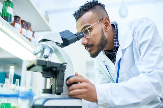 Image of a male scientist looking through a microscope