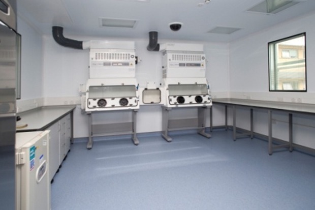 Image of an empty laboratory, showing only some work benches and two glass-fronted cabinets.