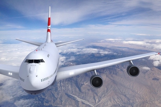 White airplane flying towards the camera in a blue sky with white clouds.