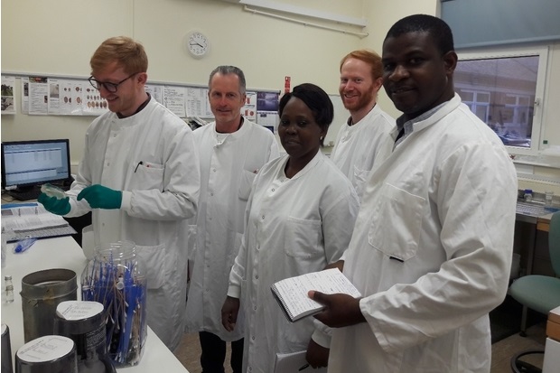 Image of four gentlemen and one lady in white coats standing in a laboratory