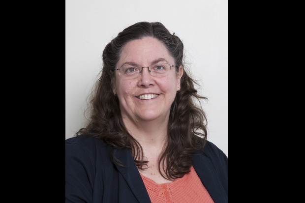 Image of Sharon Brookes wearing glasses, an orange top under a navy jacket.