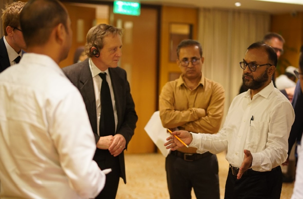 Image of a male speaking to a small group of other males