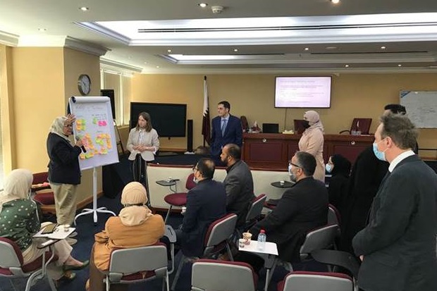 Image of a group of people listening to a lady talking at a flip chart