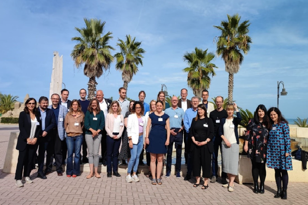 Image of a group of people against a backdrop of palm trees and blue sky