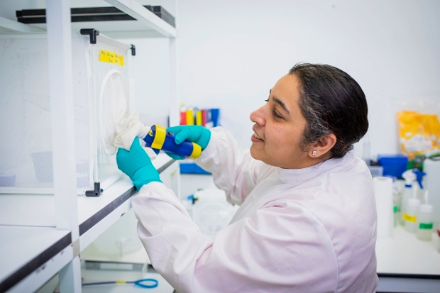 A lady with a pipette putting it into a box with netting.