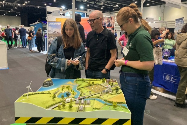 A female member of APHA staff speaking to a man and a female in front of a model landscape