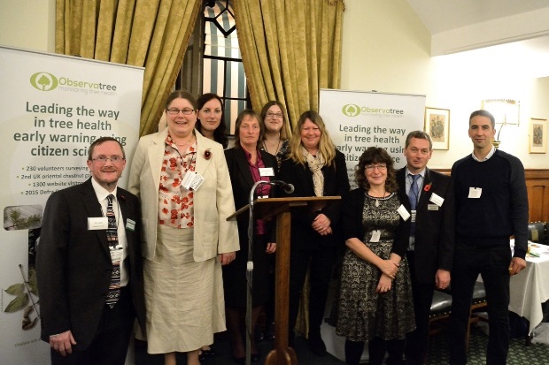 Group image of individuals standing at a lectern with Observatree pull-up banners behind them