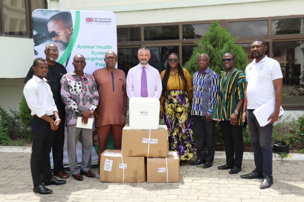 Image of individuals stood outside for a group photo behind a large pile of boxes