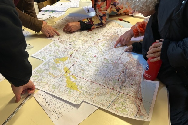 Several people engaged in discussion while studying a map laid out on a table