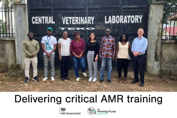 Group of individuals stading in gront of gates which say, "Central Veterinary Laboratory"