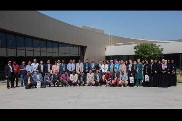 A very large group photo of individuals standing outside a large building