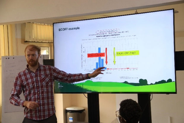 Gentleman standing in front of a large projection screen pointing to a graph