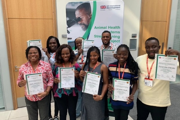 Eight individuals standing for a group photograph holding certificates.