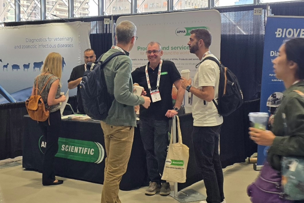 Image of two males in conversation with another male at a stand at an event, in front of an APHA Scientific backdrop and table