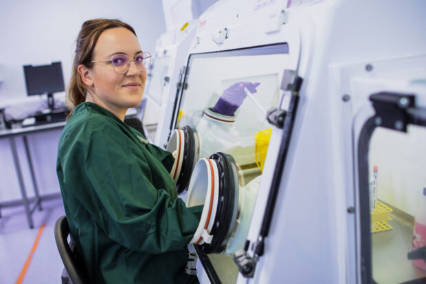 Female scientist sitting with her arms in a safety cabinet